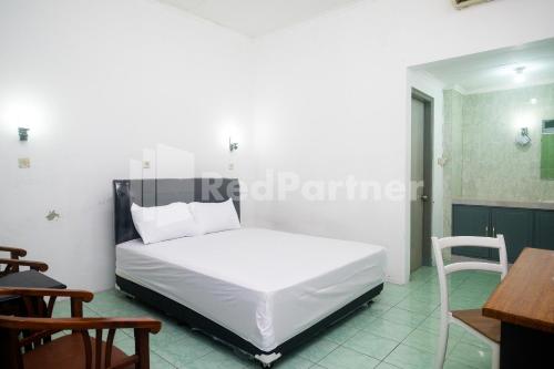 a bedroom with a white bed and a table and chairs at Camila Living Yogyakarta RedPartner in Timuran