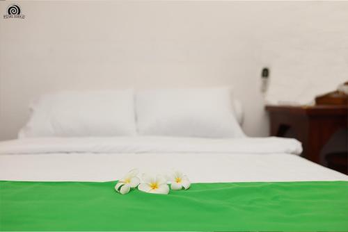 two flowers laying on top of a bed at Pearl Lodge in Polonnaruwa