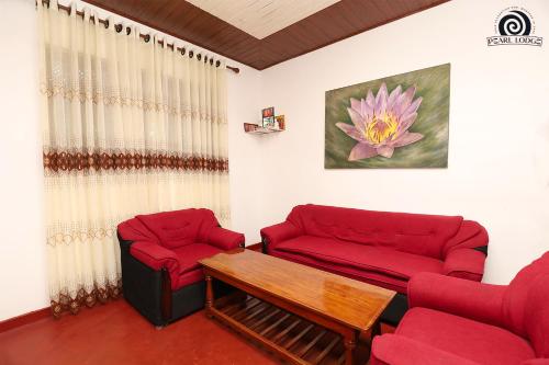 a living room with two red couches and a table at Pearl Lodge in Polonnaruwa