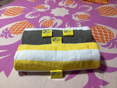 a towel on a bed with yellow and white at Bungalow climatisé chez Kim in Taputapuapea