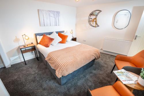 a bedroom with a bed and an orange chair at Kings Arms Suites - Luxury Double - Waterfall Shower - Self Check In in Whitehaven
