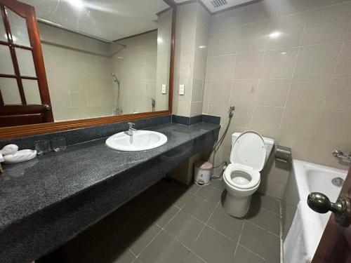 a bathroom with a sink and a toilet and a mirror at NGOC THU HOTEL in Soc Trang
