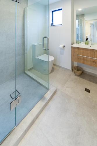 a bathroom with a glass shower and a toilet at Merivale Gem: 2BR Townhouse Oasis in Christchurch