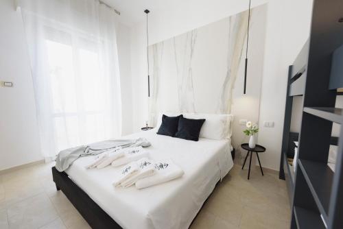 Un dormitorio con una cama blanca con toallas. en Salentin Home - SeaRelax, en San Pietro in Bevagna