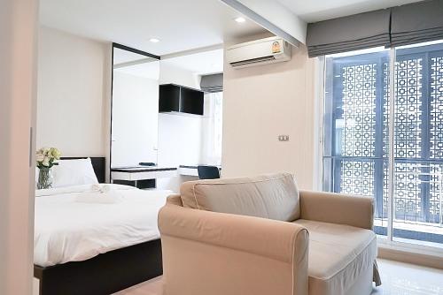 a bedroom with a bed and a couch and a chair at 5 mins to BTS Ekkamai, One Bed Fully-Furnished in Bangkok