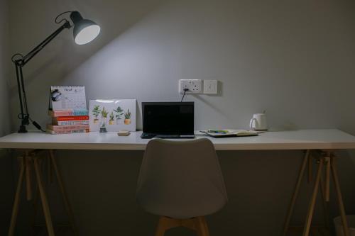 a desk with a laptop and a lamp and a chair at Bluewaters Collab Quarters in Singapore