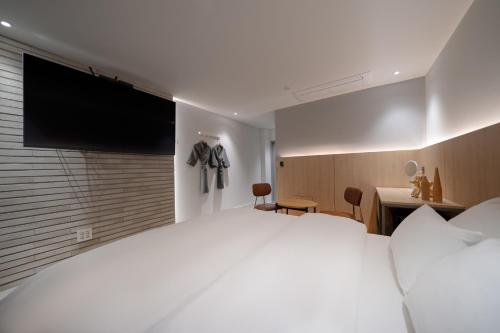 a bedroom with a large white bed and a television at Siheung Brown Dot Jeongwang in Siheung