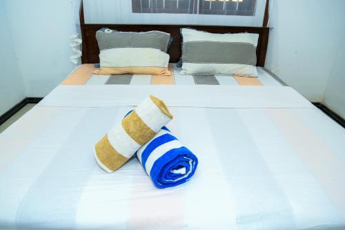 a white bed with a blue and white towel on it at Eton Villa Talpe in Talpe