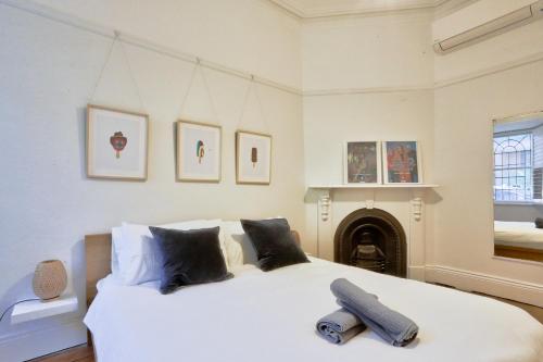 1 dormitorio con 1 cama blanca grande y chimenea en 2 Bedroom House Situated at the Centre of Surry Hills 2 E-Bikes Included en Sídney