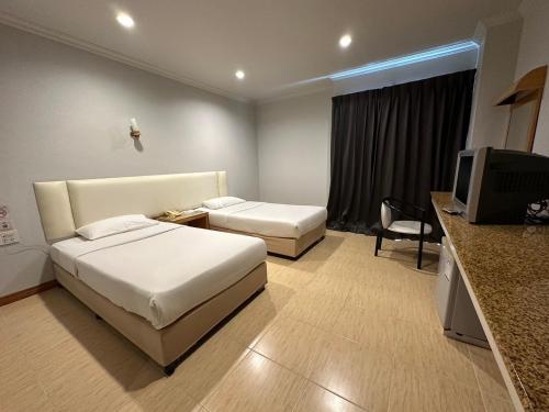 a hotel room with two beds and a television at Rattana View in Phitsanulok