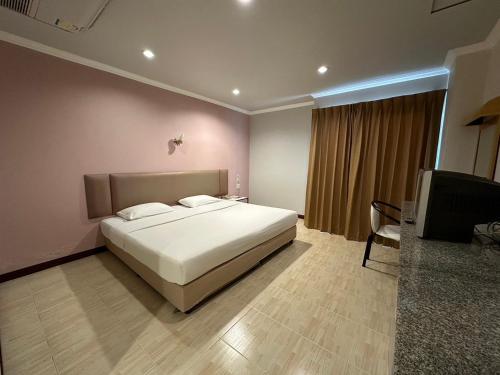 a bedroom with a large white bed and a chair at Rattana View in Phitsanulok
