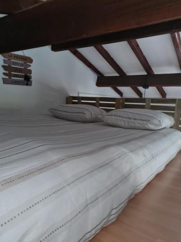 a large bed with white sheets and pillows on it at Maison calme proche étang in La Coquille