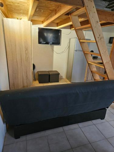Cette chambre dispose d'un canapé, d'une télévision et d'une échelle. dans l'établissement Maison calme proche étang, à La Coquille