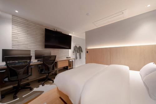 a bedroom with a bed and a desk with a computer at Siheung Brown Dot Jeongwang in Siheung