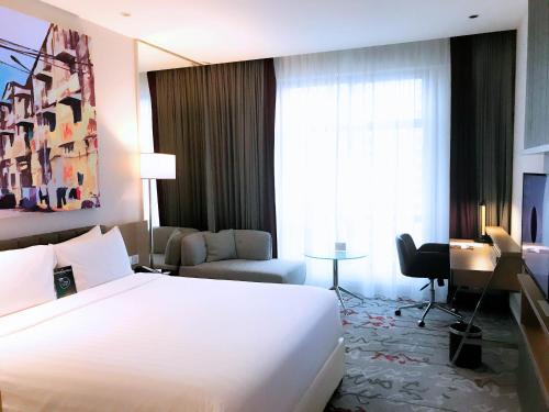 a hotel room with a large white bed and a desk at Mercure Kuala Lumpur Shaw Parade in Kuala Lumpur