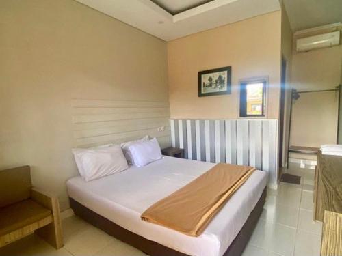 een slaapkamer met een bed en een stoel bij Roemah kita hotel in Ngaglik