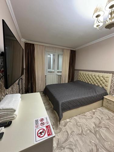 een kamer met een bed en een tafel met een televisie bij Апартаменты люкс класса in Karagandy