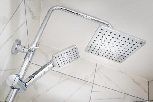 a shower head in a bathroom with white tiles at Kings Arms Suites - Deluxe Room - En-Suite - Self Check In in Whitehaven