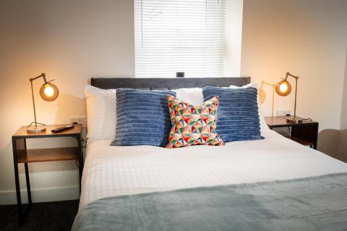 a bed with blue and white pillows and two lamps at Kings Arms Suites - Deluxe Room - En-Suite - Self Check In in Whitehaven