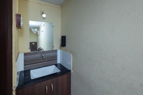a bathroom with a sink and a mirror at Hotel Ambika in Kolhapur