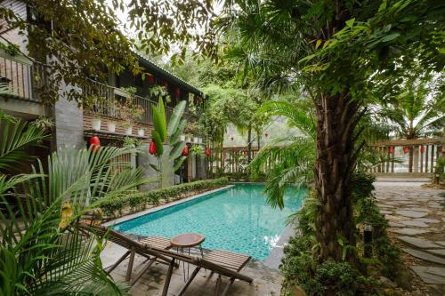 a swimming pool with two chairs and a tree at King Kong Homestay in Ninh Binh