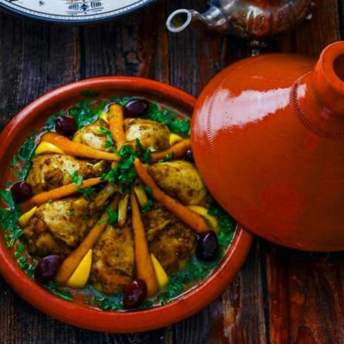 a bowl of food with chicken and vegetables on a table at Holiday Desert Camp in Merzouga