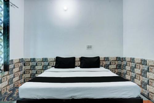 a white bed with black pillows on top of it at OYO Jatin Hotel And Restaurant in Rewāri