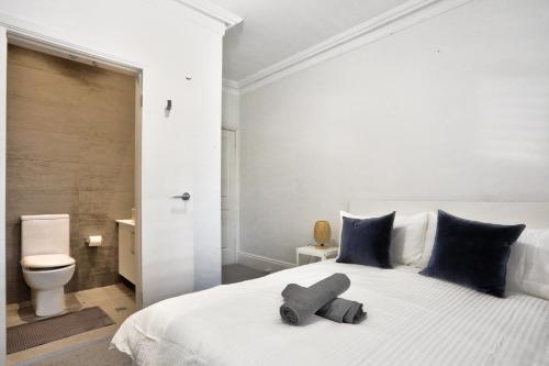 1 dormitorio con 1 cama blanca grande con almohadas azules en Good for Family 3 Bedroom House Darlinghurst with 2 E-Bikes Included, en Sídney