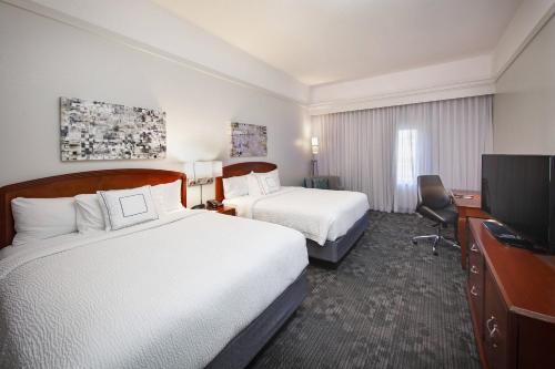 a hotel room with two beds and a flat screen tv at Courtyard by Marriott Valdosta in Valdosta