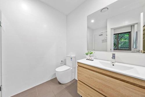 a bathroom with a sink and a toilet and a mirror at Rooftop 2 Bed Apt With Terrace at Newtown in Sydney