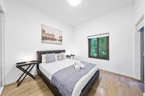 a white bedroom with a bed and a window at Rooftop 2 Bed Apt With Terrace at Newtown in Sydney