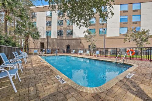 a swimming pool with chairs and a building in the background at Four Points by Sheraton Jacksonville Baymeadows in Jacksonville