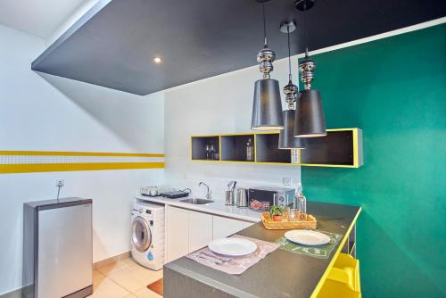 a kitchen with green and white walls and a counter at Arte Plus KLCC Designer Suites by Cobnb in Kuala Lumpur
