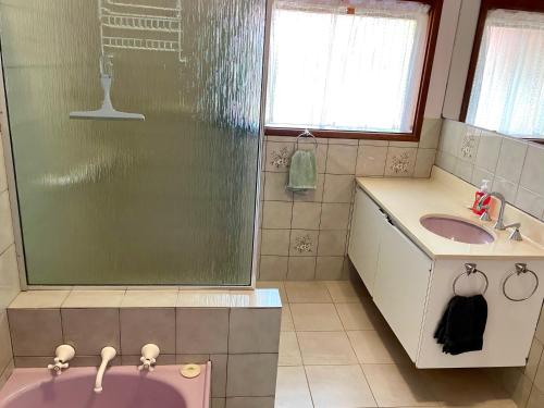 ein Bad mit einer Badewanne, einem Waschbecken und einer Dusche in der Unterkunft Lacey's Holiday House in Kingscote