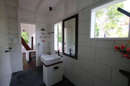 baño blanco con lavabo y ventana en Sugar Mountain Cottage, en Saint Mary