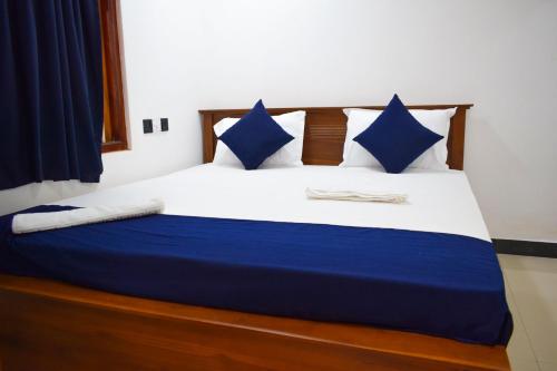 Schlafzimmer mit einem Bett mit blauen und weißen Kissen in der Unterkunft ROLEX GUEST HOUSE in Trincomalee