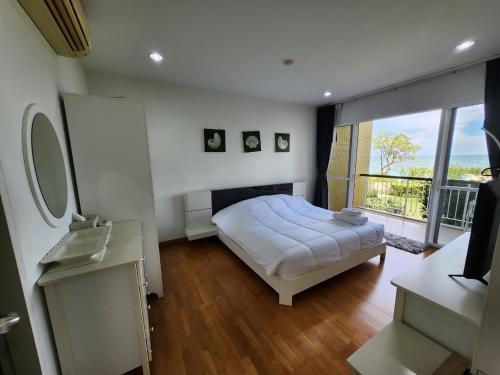 a bedroom with a bed and a large window at Baan Ploen Talay (บ้าน เพลินทะเล ชะอำ) in Cha Am