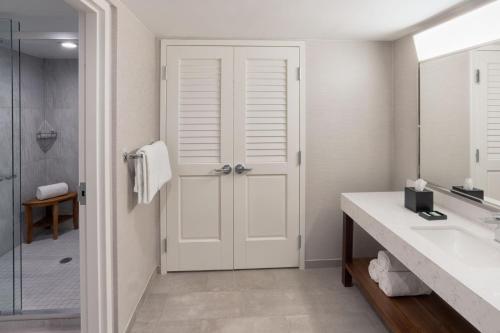 a bathroom with a shower and a white door at Courtyard by Marriott Fort Lauderdale East / Lauderdale-by-the-Sea in Fort Lauderdale