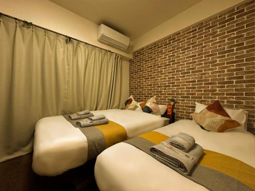 a room with two beds and a brick wall at nestay apartment tokyo ikebukuro in Tokyo