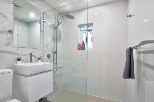 a white bathroom with a shower and a sink at Ideal 3 Bedroom House in Chippendale with 2 E-Bikes Included in Sydney