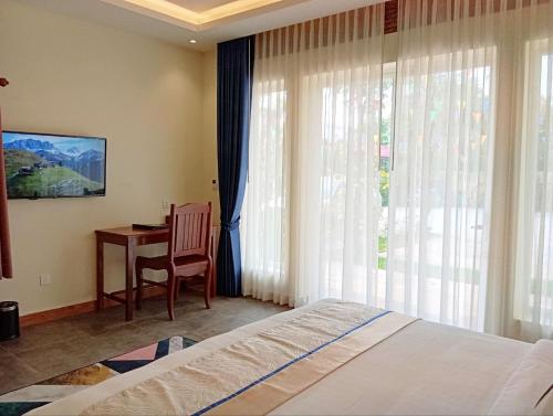a bedroom with a bed and a desk and a window at Sokchea Kampot Hotel in Kampot