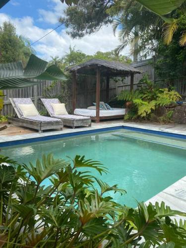 a swimming pool with two chairs and a gazebo at CC's @ Byron Self Contained Studio in Byron Bay