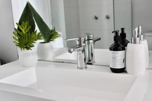 a bathroom sink with two bottles of soap and a mirror at CC's @ Byron Self Contained Studio in Byron Bay