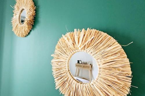 a wicker mirror on a green wall with a table at Lilas Rose in Thonon-les-Bains