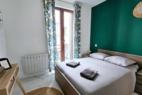 a bedroom with a large bed with a green wall at Lilas Rose in Thonon-les-Bains