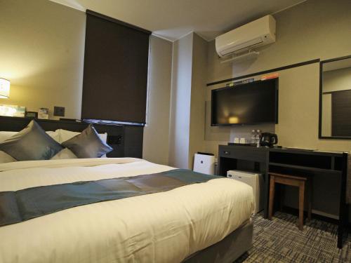 a hotel room with a bed and a flat screen tv at Astil Hotel Shinosaka Precious in Osaka