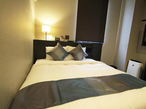 a bedroom with a large white bed with pillows at Astil Hotel Shinosaka Precious in Osaka
