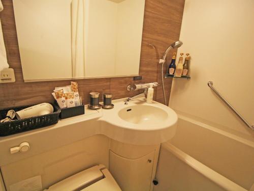 a bathroom with a sink and a toilet and a mirror at Astil Hotel Shinosaka Precious in Osaka