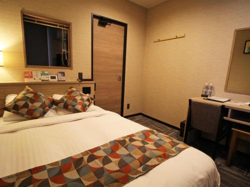 a hotel room with a bed and a desk and a television at Astil Hotel Shinosaka Precious in Osaka