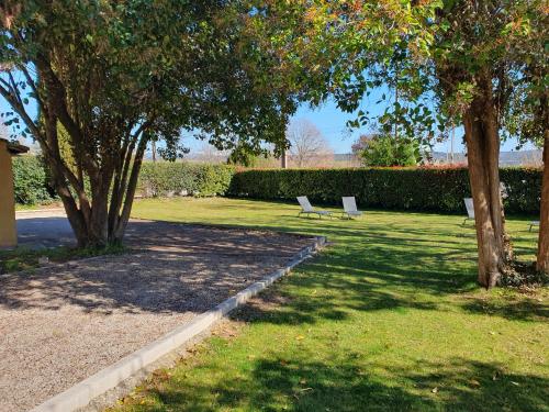 two white chairs sitting in a park with trees at Le Mas des Quintrands Manosque - Motel de charme in Manosque
